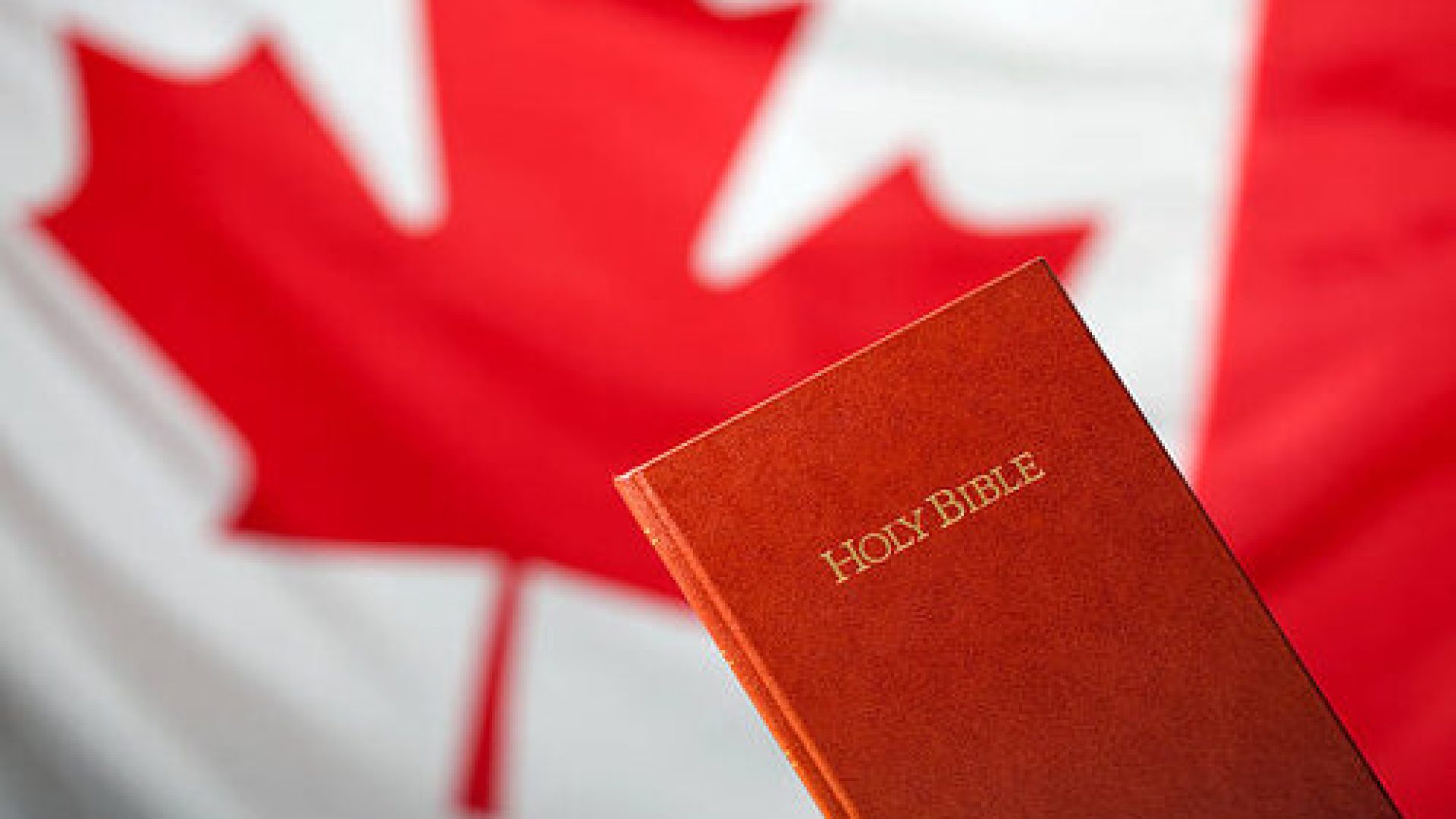 Bible and Canadian flag in the background. Selective focus.